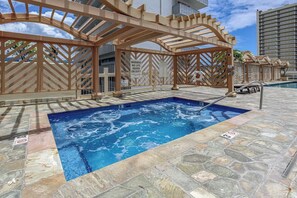 A hot tub area with a pool, wooden pergolas, and a warning sign.