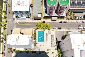 Luftaufnahme eines Stadtkreuzung mit Schwimmbecken, Gebäuden und parkenden Autos.