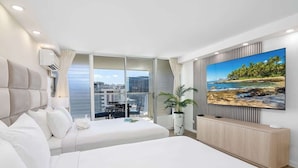 Een moderne hotelkamer met twee bedden, een groot raam, een balkon en een televisie aan de muur.
