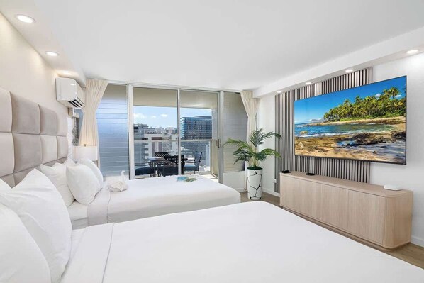 A modern hotel room with two beds, a large window, a balcony, and a television on the wall.
