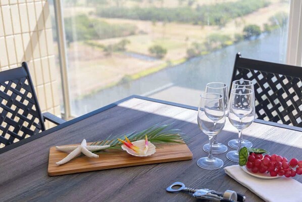 Una mesa con una estrella de mar, una concha decorativa y una fuente de uvas, con dos copas de vino vacías y un abrelatas.