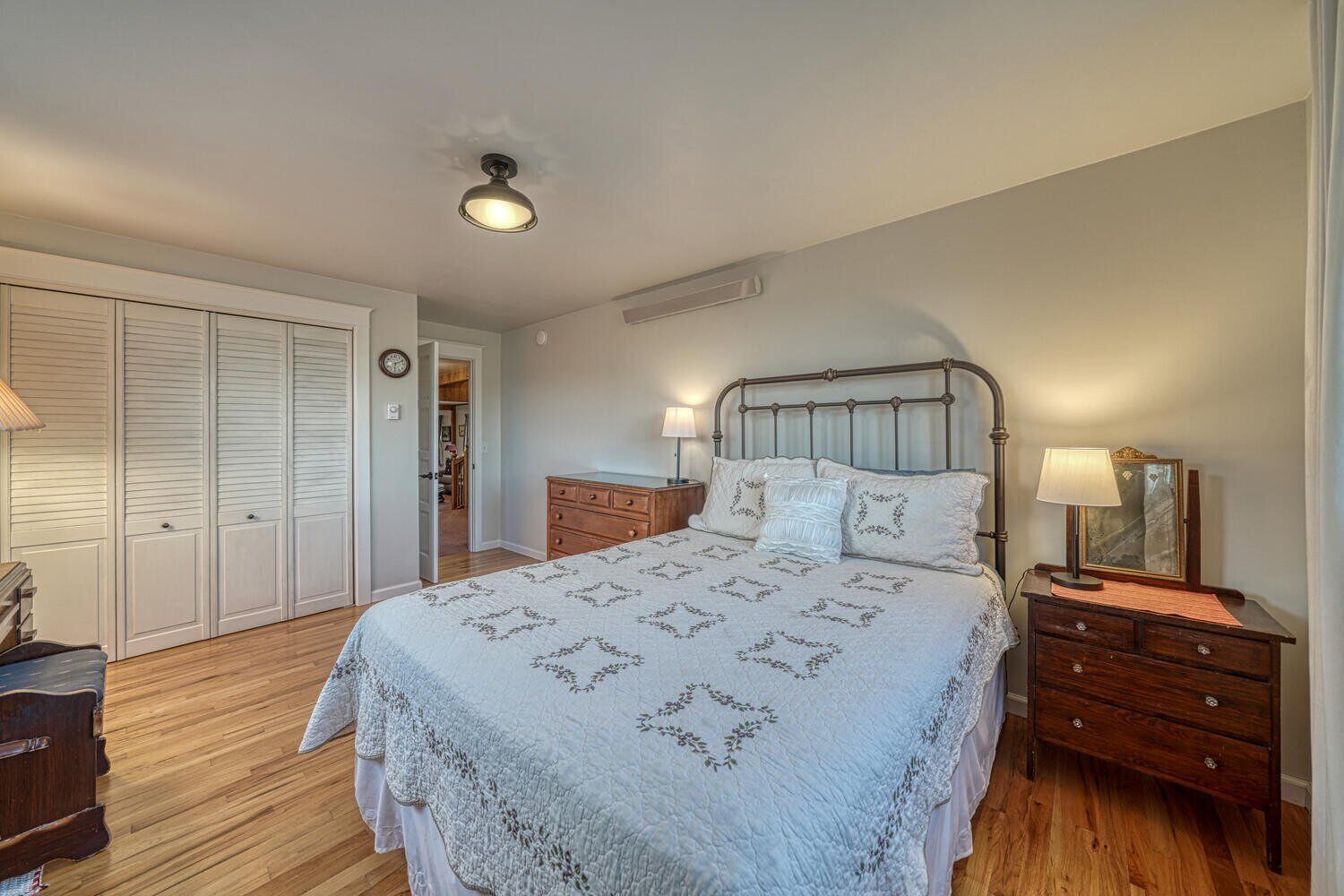 Une chambre à coucher comprenant un lit, des tables de chevet, une commode et un placard.