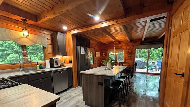 A wooden cabin kitchen with a central island, built-in appliances, and a view of the outdoors. - Modern, 2 King, 4 BDRM Private Luxury Log Cabin, 5 Star, Family Friendly (Intervale)