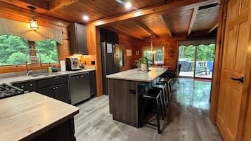 A wooden cabin kitchen with a central island, built-in appliances, and a view of the outdoors.