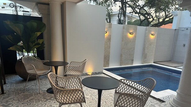 Un espacio al aire libre con suelo estampado, una piscina e iluminación decorativa.