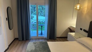 Habitación de hotel con cama, una pequeña mesa, una silla, un espejo y vistas a un balcón con mesa y sillas afuera.