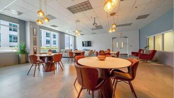 A modern conference room with round tables and chairs, large windows, and hanging pendant lights.