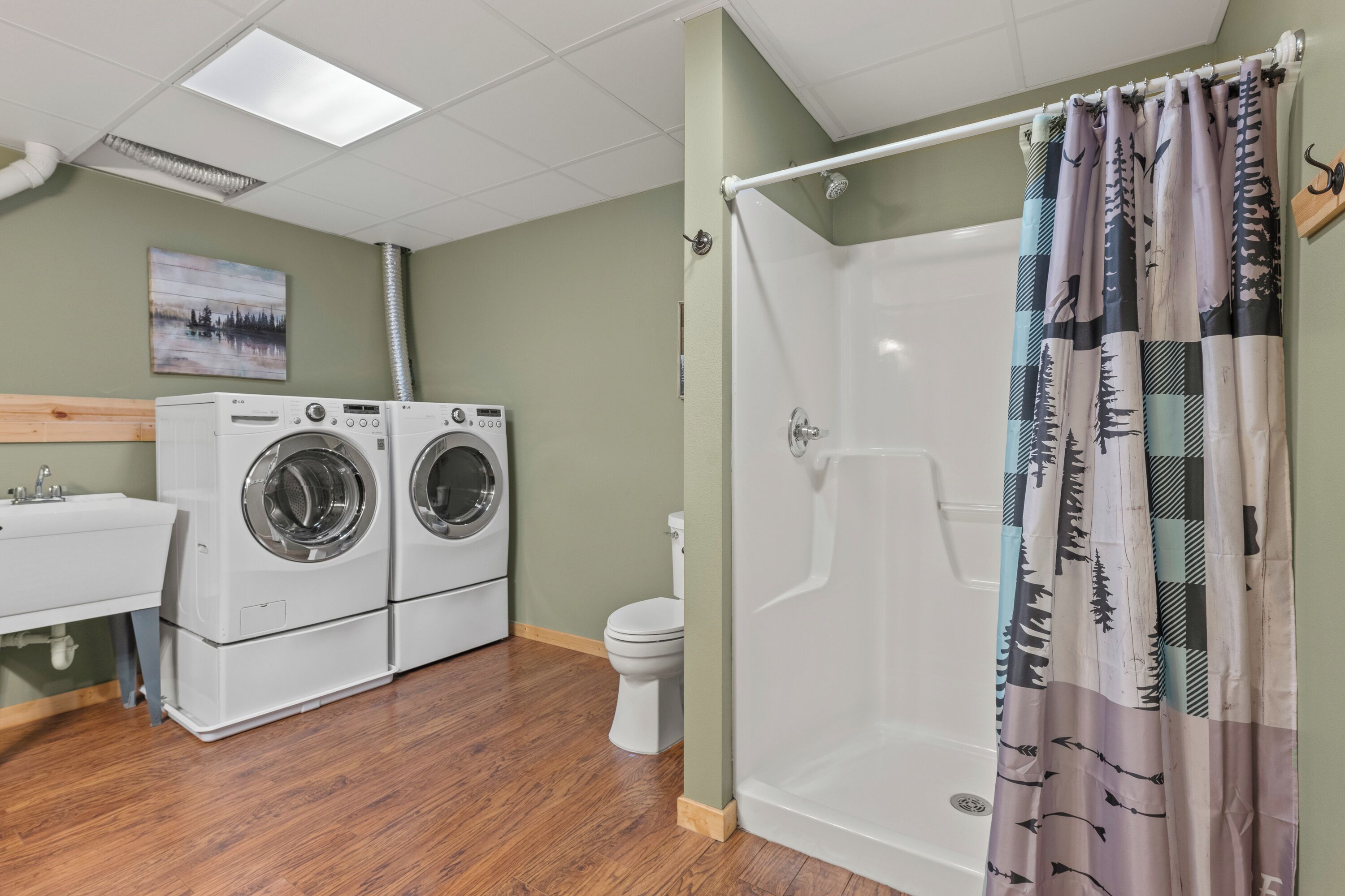 Un baño con ducha, inodoro y lavadora.