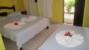 A hotel room with two beds, each with a towel arranged in a fan shape and a red flower in the center. - Pousada Vila do Zimbo (Cairu)