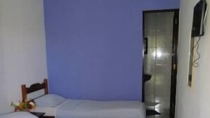 A room with two single beds, a wooden headboard, a small table with a vase, and a mirror on the wall. - Pousada Vila do Zimbo (Cairu)