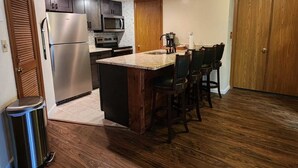 A modern kitchen with dark wood cabinets, stainless steel appliances, and a central island with bar stools. - Cozy condo, Family- friendly just completely remodeled. SKI IN -SKI OUT!! (Champion)