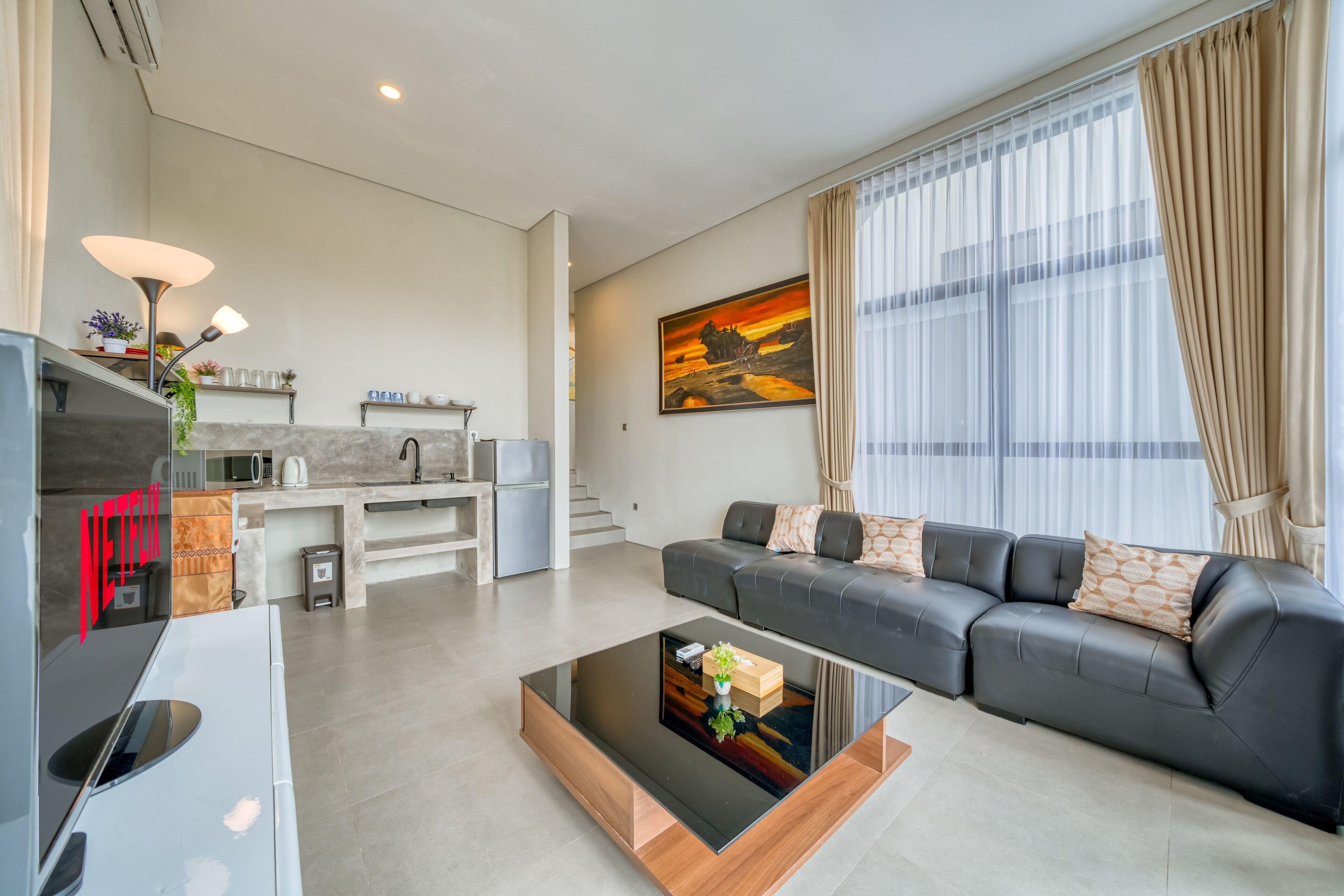 Een moderne woonkamer met een bank, een salontafel en een keuken op de achtergrond.
