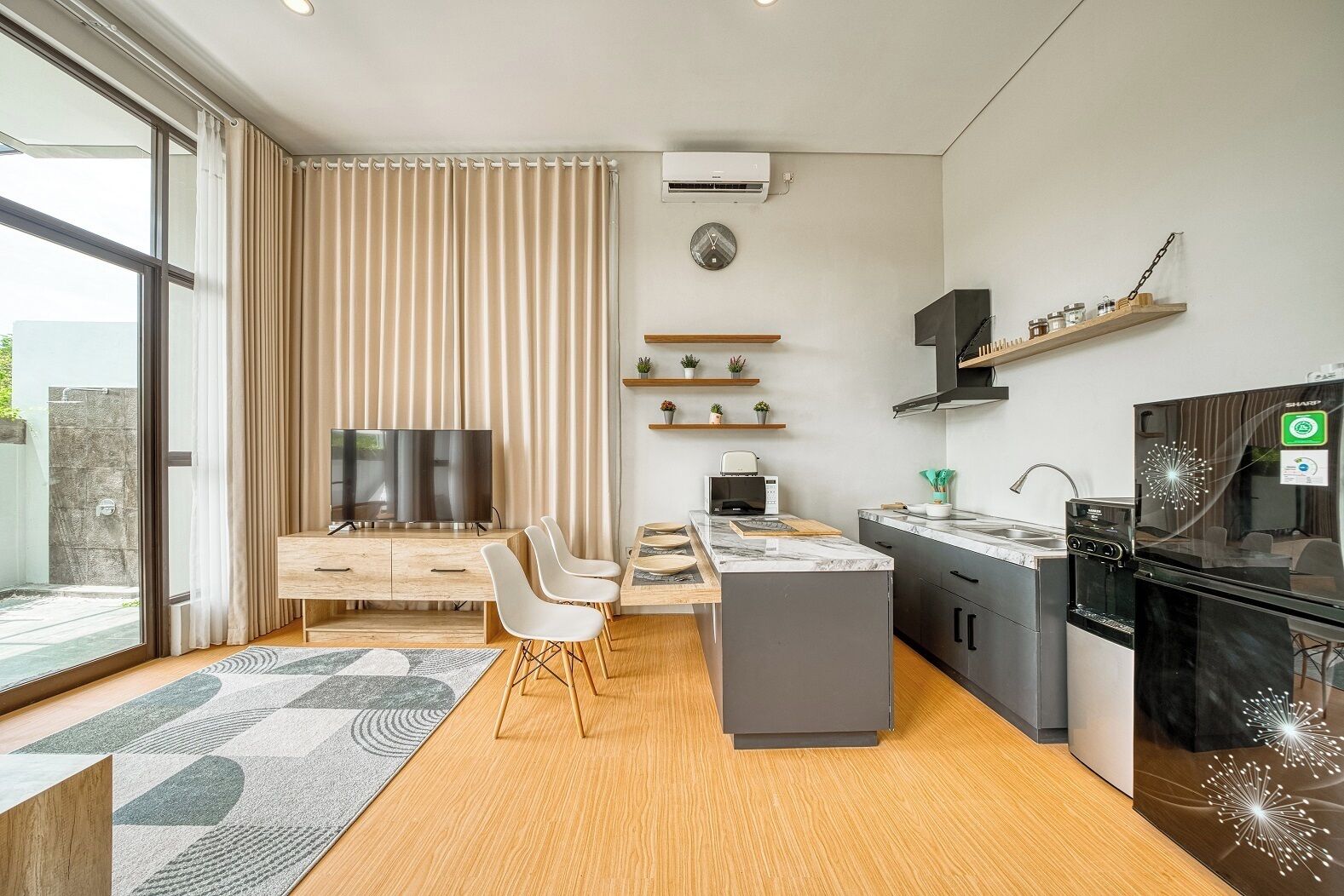 A modern kitchen with a built-in oven, a microwave, and a coffee machine. There is a dining area with a table and chairs.