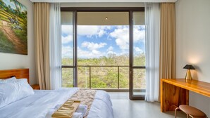 A hotel room with a large bed, a wooden desk, and a view of the outdoors. - Residence at Damara Village Jimbaran (Jimbaran)