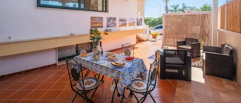 An outdoor patio with a table set for dining, surrounded by wicker furniture.