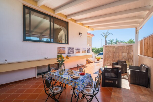 An outdoor patio with a table set for dining, surrounded by wicker furniture.