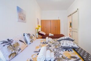 A bedroom with a bed, pillows, a wooden wardrobe, and a wall art piece.