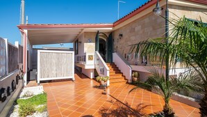 A house with a tiled patio, a staircase, and a covered entrance. - Villa 'Malva House In  Con Piscina' with Shared Pool, Wi-Fi and Air Conditioning (Scala di Furno)