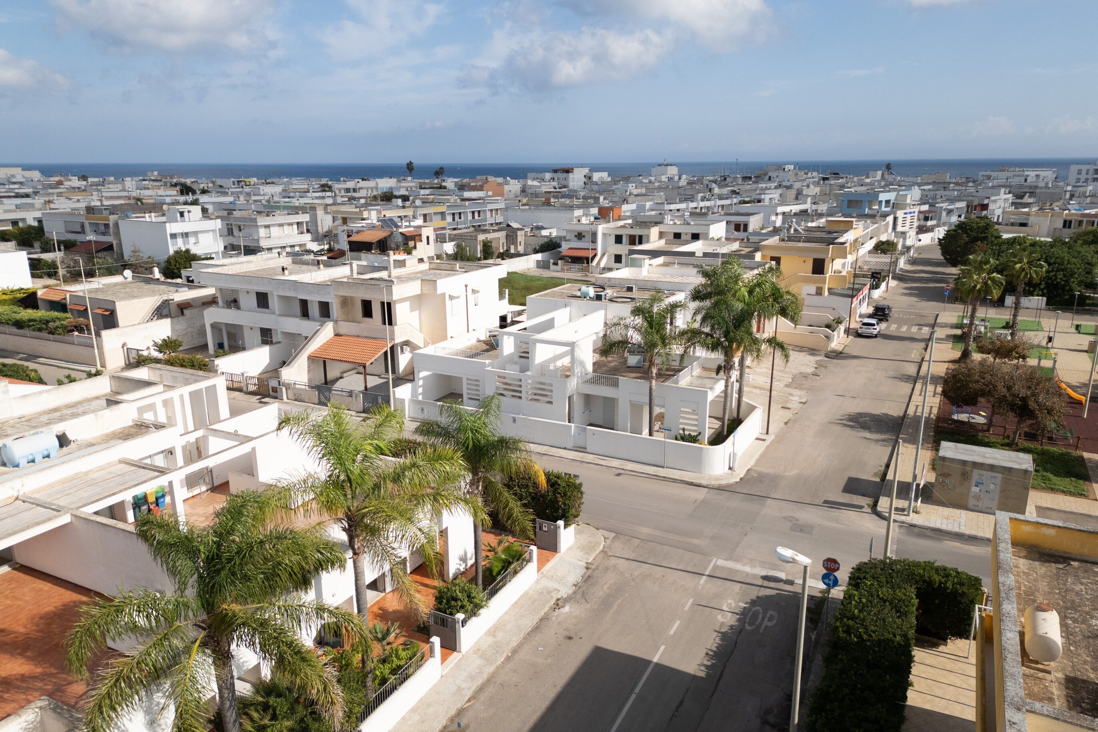 Zona residencial con edificios blancos, palmeras y una vista despejada del mar.