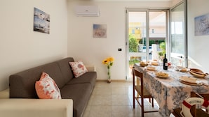 Una sala moderna con un sofá, una mesa de comedor para cuatro comensales y vistas a través de un ventanal.