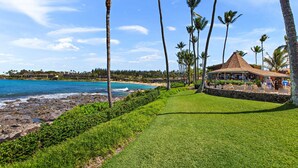 A coastal resort with a beach, palm trees, and a gazebo.