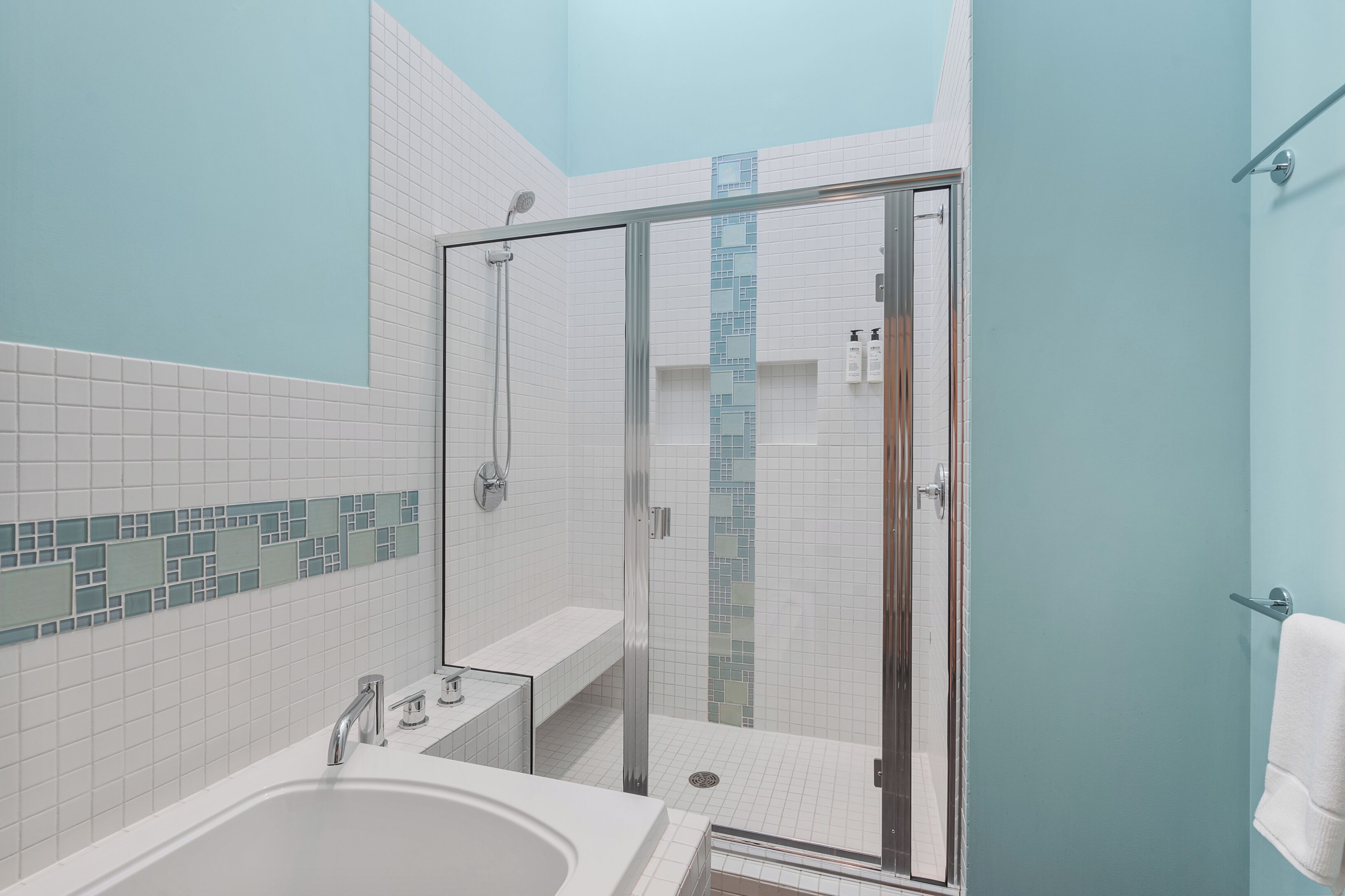A modern bathroom with a glass-enclosed shower, a bathtub, and a sink.