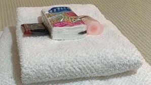 A bed with a white textured blanket, a stack of magazines, and a pink object on it. - Flat na rua Bela Cintra (São Paulo)