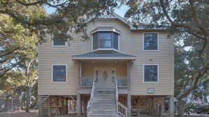 A two-story house with a front porch, a central entrance, and a small staircase leading up to the entrance. - 2507 - Salty Sandpiper - Coastal Retreat in Duck | Hot Tub & Sunsets (Duck)