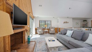 A living room with a sofa, coffee table, TV, and patterned rug. - 2507 - Salty Sandpiper - Coastal Retreat in Duck | Hot Tub & Sunsets (Duck)