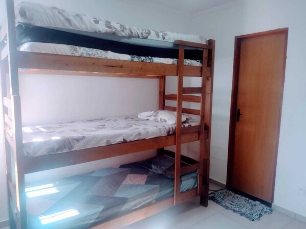 A bunk bed with a wooden ladder, a door, and a patterned bedspread.