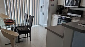 A modern kitchen with white cabinets, a built-in oven, and a gas stove. There is a dining area with a table and chairs, and a large window with blinds. - Great Specials Now! PET Friendly, 2 Bedroom, 2 Bath Home, 10 min. from The Strip (Las Vegas)