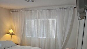 A bedroom with a bed, a window with blinds, a bedside lamp, a radiator, and a small mat on the floor. - Great Specials Now! PET Friendly, 2 Bedroom, 2 Bath Home, 10 min. from The Strip (Las Vegas)