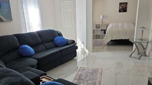 A living room with a dark sofa set, a ceiling fan, a bed, and a small table with a lamp. - Great Specials Now! PET Friendly, 2 Bedroom, 2 Bath Home, 10 min. from The Strip (Las Vegas)