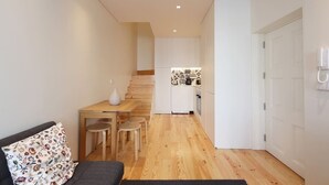 A compact living space with a kitchenette, a dining area, and a sofa. - HM - Pinheiro Duplex Apartment (Porto)