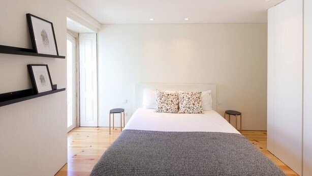A modern bedroom with a large bed, a grey blanket, and two bedside tables. - HM - Pinheiro Duplex Apartment (Porto)