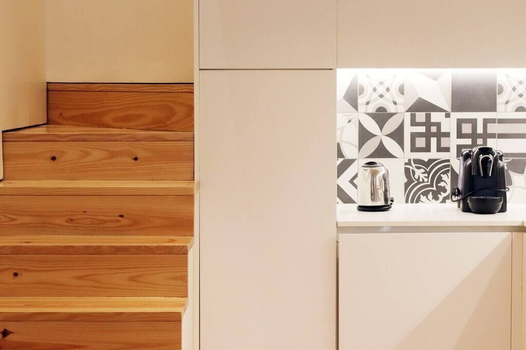 A kitchen with a patterned backsplash, a coffee maker, and a kettle on the counter.