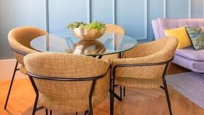 A dining area with a round glass table, four wicker chairs, and a potted plant. - HM - Infante Riverside Apartment M (Porto)