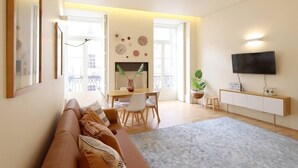 Una sala de estar moderna con un sofá, una mesa de comedor, sillas, un televisor y una chimenea.