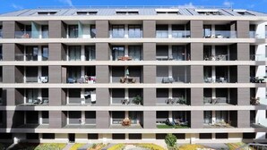 Ett hotell med flera våningar, balkonger, utomhusservering och en vackert anlagd trädgård.