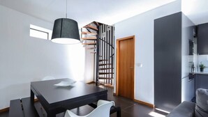 A modern living space with a dining area, a staircase, and a kitchen. - Panoramic River View Downtown With Terrace (Porto)