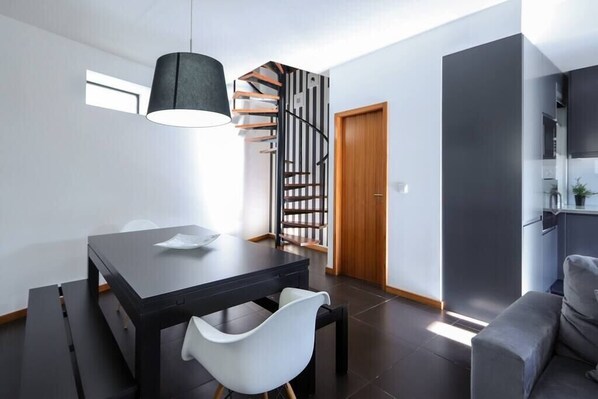 A modern living space with a dining area, a staircase, and a kitchen.