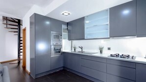 A modern kitchen with grey cabinets, a built-in oven, and a stainless steel sink. - Panoramic River View Downtown With Terrace (Porto)