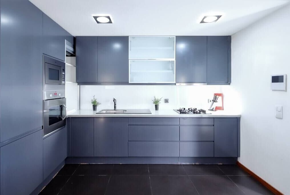 Una cocina moderna con armarios grises, horno empotrado, microondas y un lavamanos.