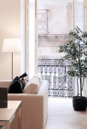 A modern living room with a sofa, a table, and a potted plant. - HM - Ribeira São João Apartment - 3F (Porto)