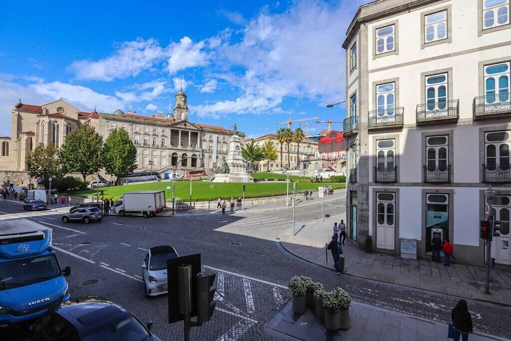A city intersection with historic buildings, a tram, and a pedestrian crossing.