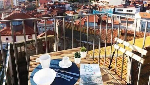 Terrassa al terrat amb taula preparada per a dues persones, amb vista a un paisatge urbà.