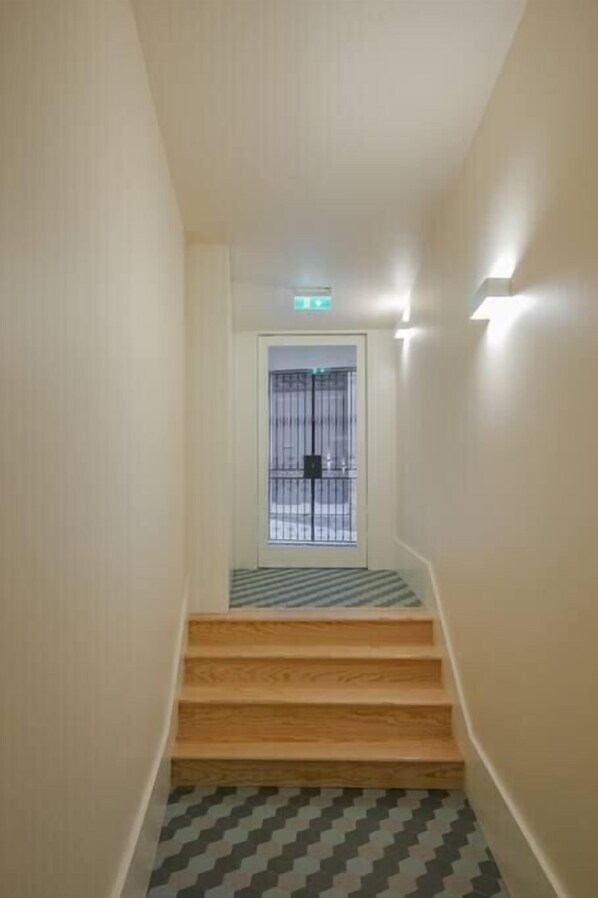 A staircase with wooden steps leading to a door with a metal gate.