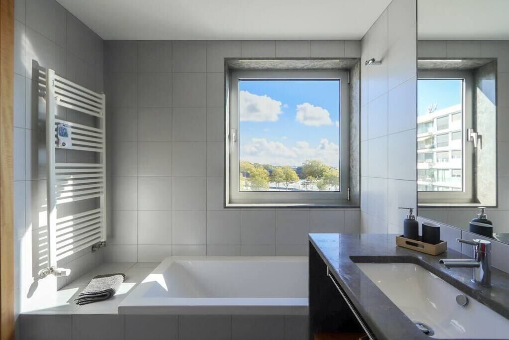 A modern bathroom with a bathtub, a large window, and a built-in shelf with toiletries.