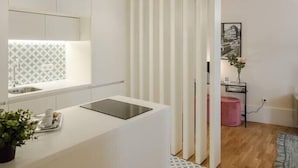 A modern kitchen with a white countertop, a built-in stove, and a pendant light. - HM - Ribeira São João Apartment - 2D (Porto)