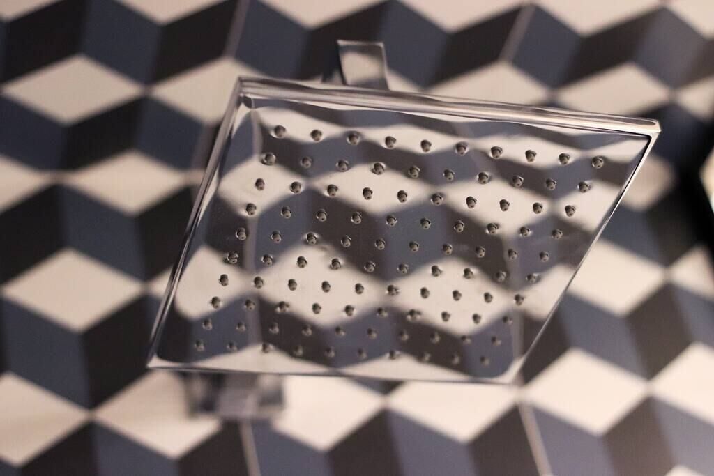 A showerhead with a square shape and multiple holes.